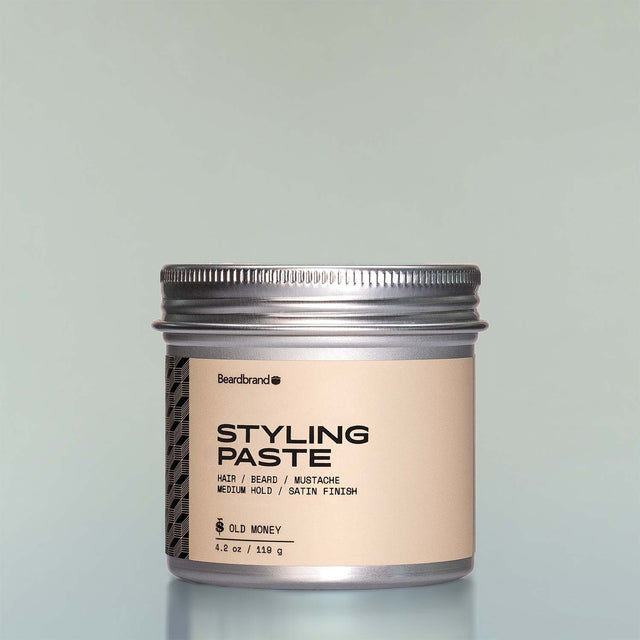 A container of Old Money Styling Paste against a grey background.