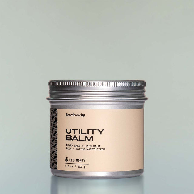 A container of Old Money Utility Balm against a grey background.