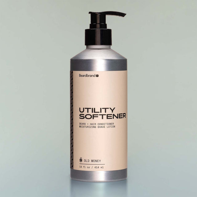 A bottle of Old Money Utility Softener with a pump dispenser against a grey background.
